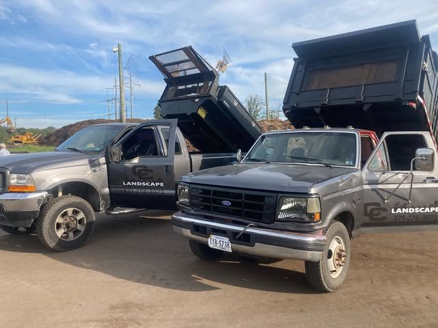 Two C & C Landscape pickup trucks with dump bodies and the C & C logo on the doors