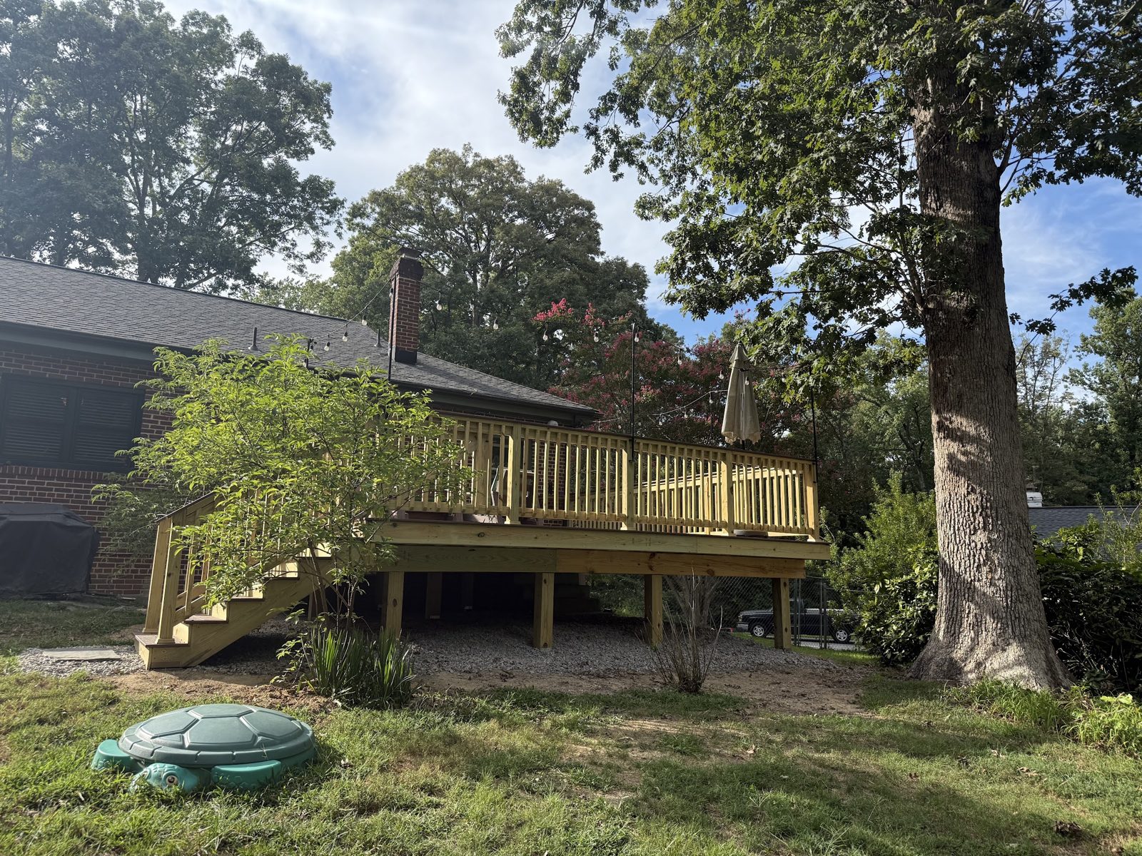A raised backyard deck with stairs, seen from the lawn