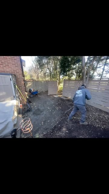 C & C crew member digging a drainage trench along a backyard fence